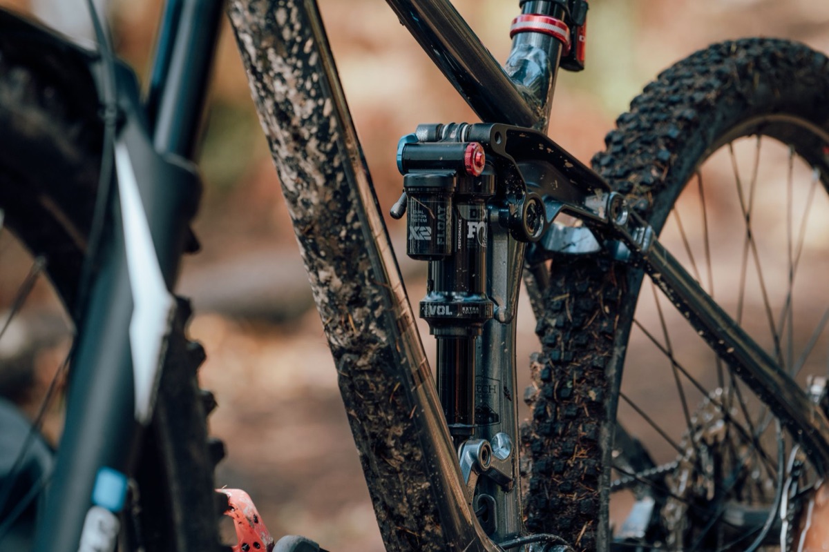 Detailed view of a mountain bike with muddy suspension fork in a natural outdoor setting.