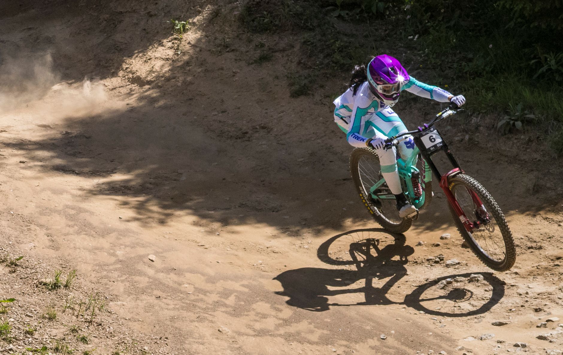 Downhill racer railing a dry, dusty berm on a Trek Session, dust kicking off the rear wheel.