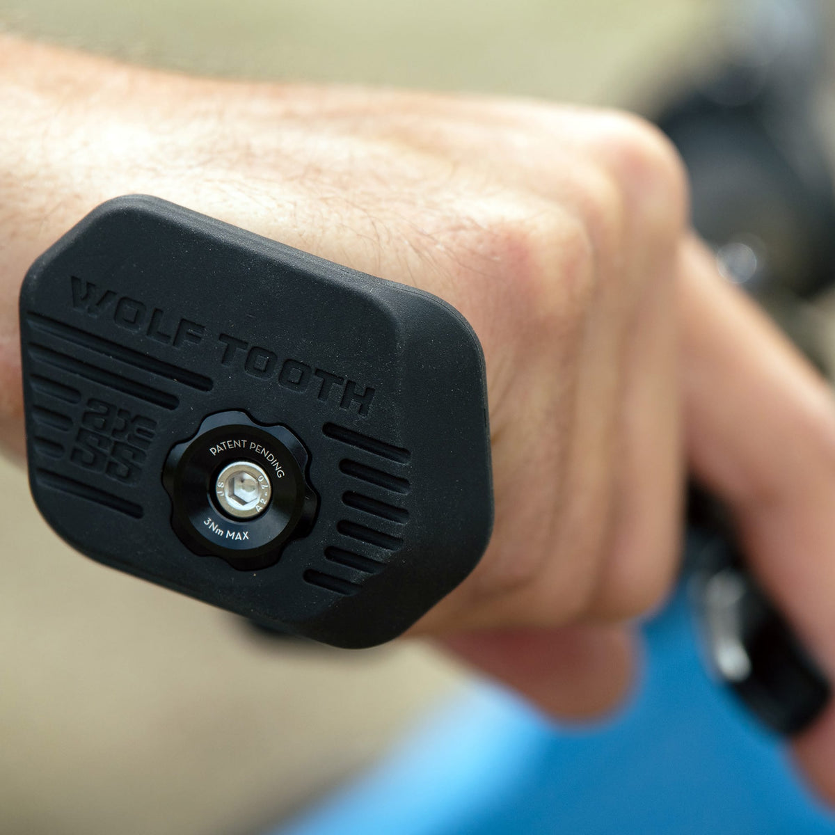 Close-up of a Wolf Tooth Locked-In bar end sitting against the outside edge of a hand on the handlebar.
